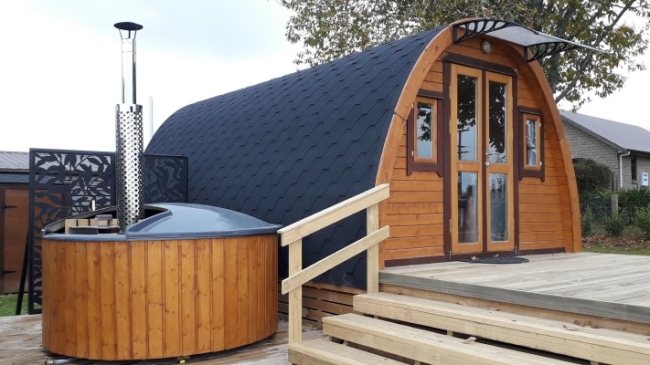 Wooden glamping pod with curved roof beside wood-fired hot tub on decking | Signature Garden Rooms, Central Scotland