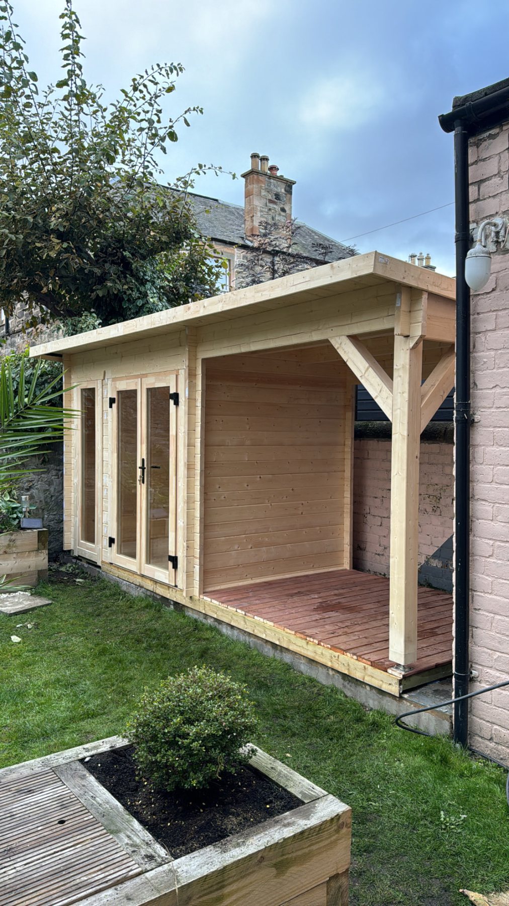 Light timber log cabin featuring glazed double doors and attached covered side canopy | Signature Garden Rooms, Central Scotland