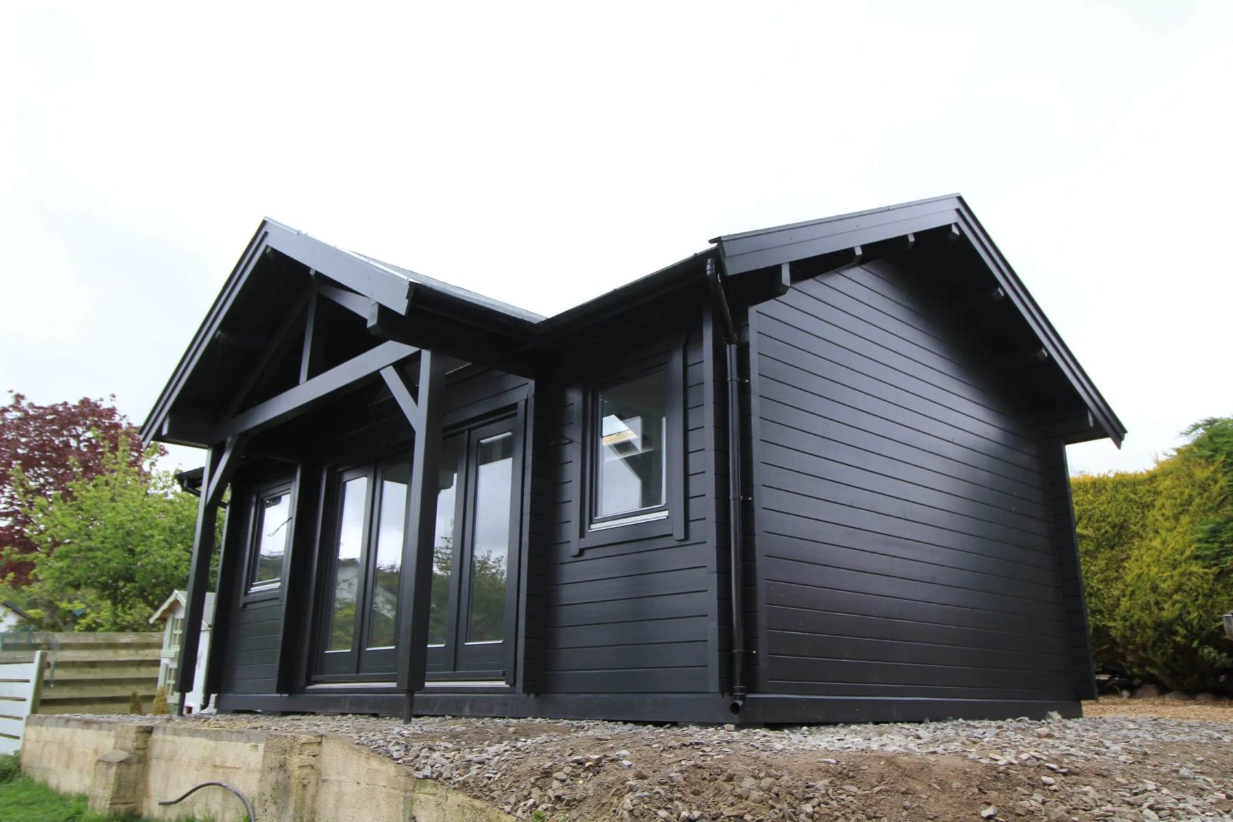 Black painted log cabin with apex roof, covered porch, and double glass doors | Signature Garden Rooms, Central Scotland