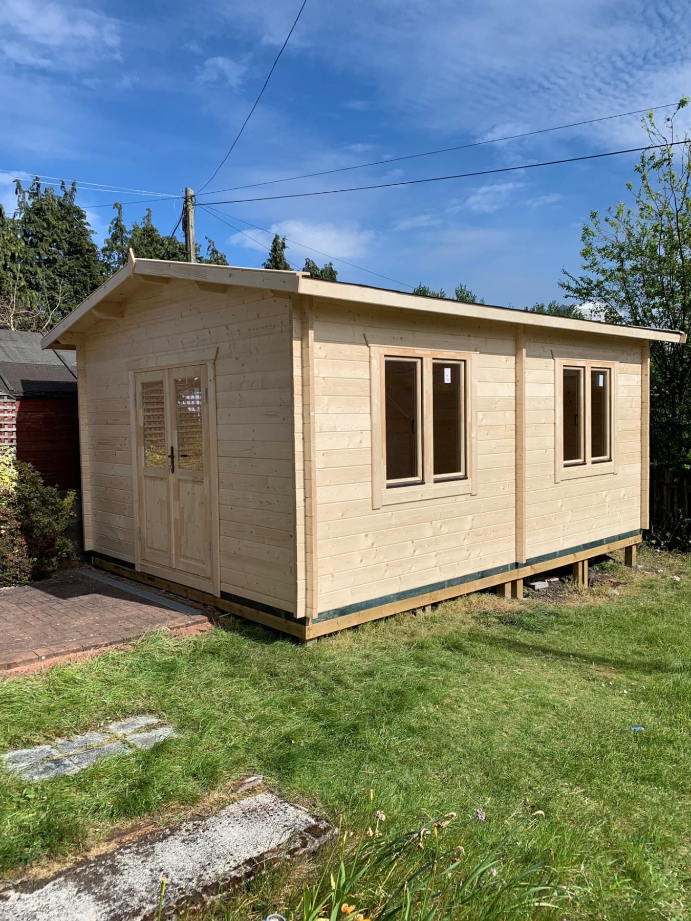 Large light timber log cabin with double doors and windows in a grassy garden | Signature Garden Rooms, Central Scotland