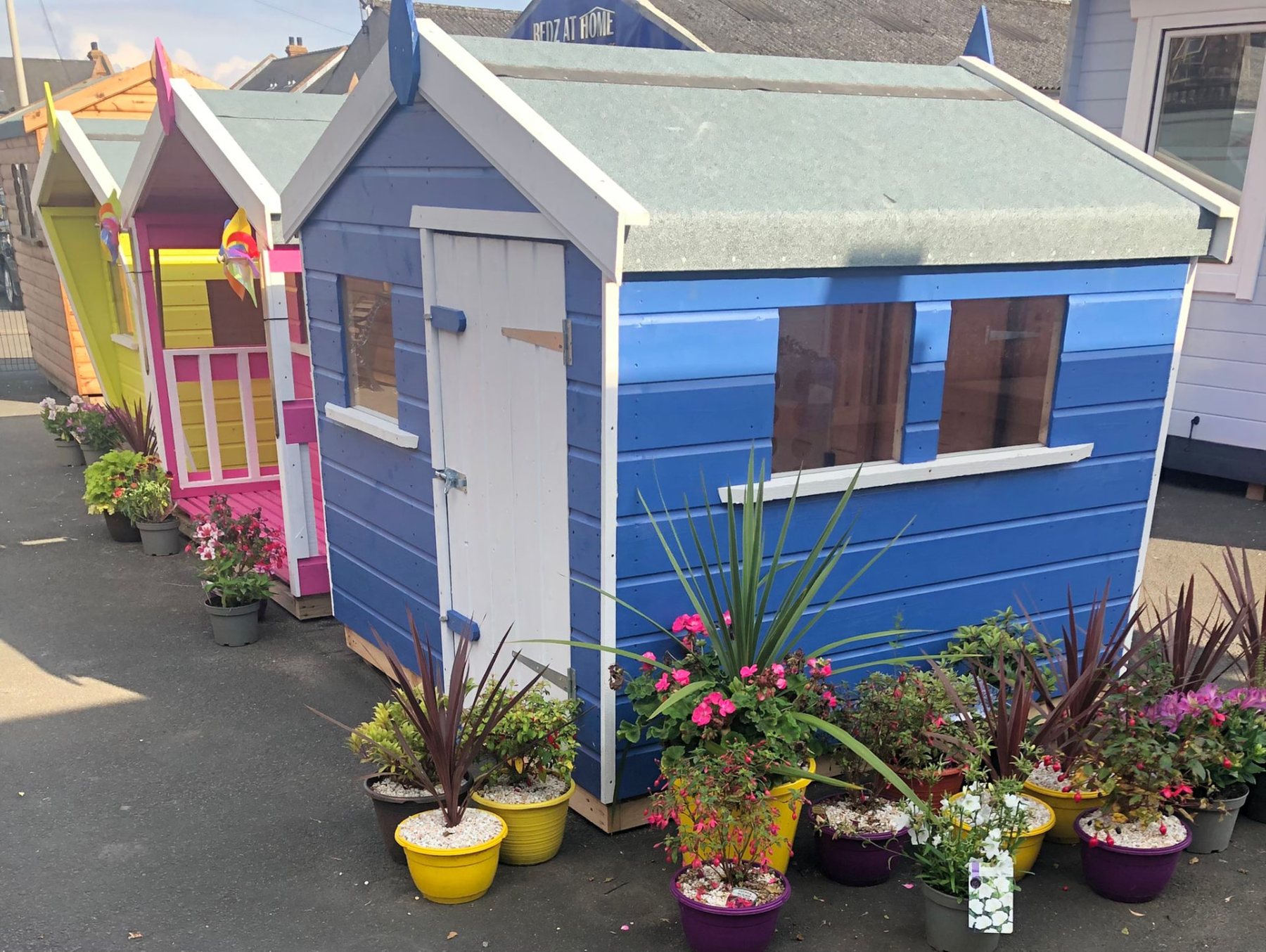 A small blue painted wooden playhouse on display with potted plants | Signature Garden Rooms, Central Scotland