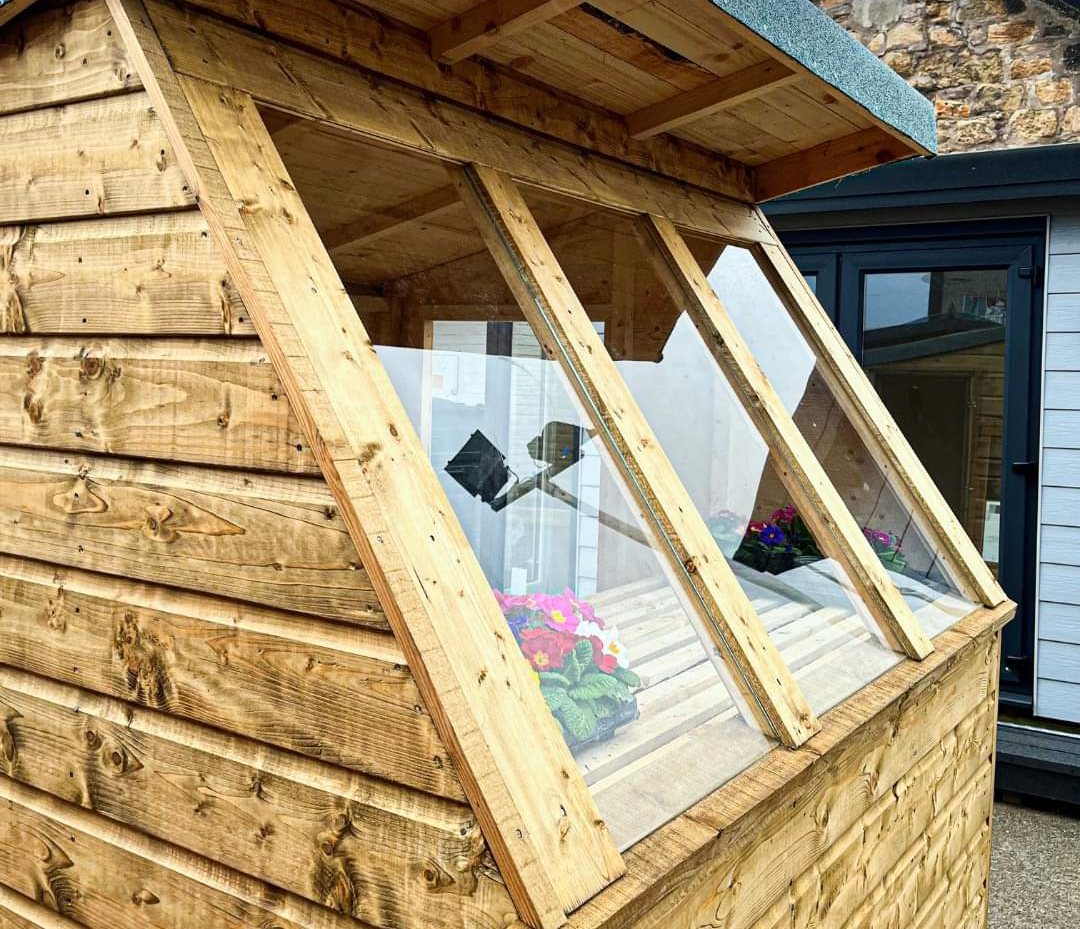 Wooden potting shed with angled glass windows featuring interior staging and potted flowers | Signature Garden Rooms, Central Scotland