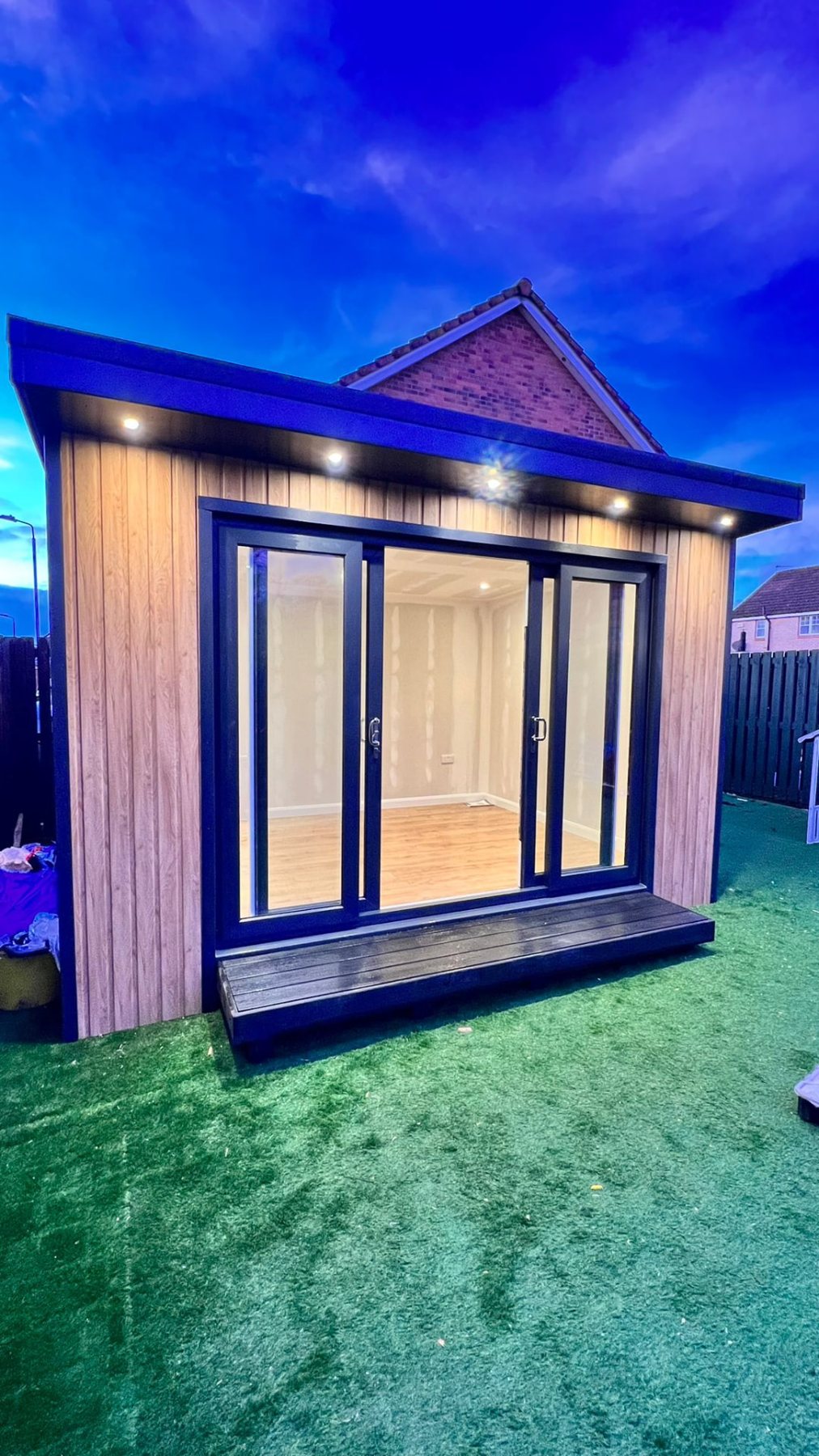 Modern timber clad garden room with open sliding glass doors at twilight | Signature Garden Rooms, Central Scotland