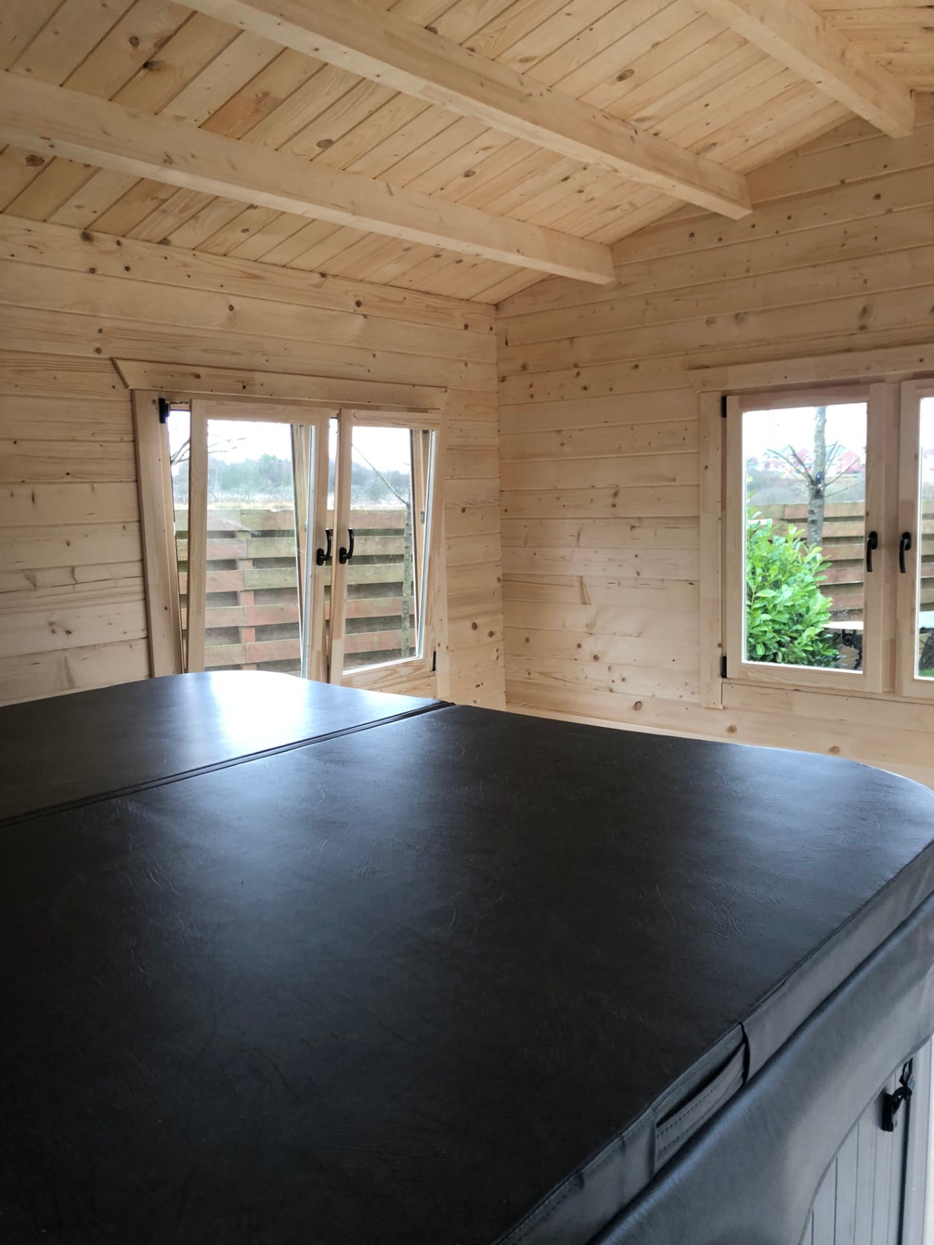 Interior view of a timber cabin room with a covered hot tub | Signature Garden Rooms, Central Scotland