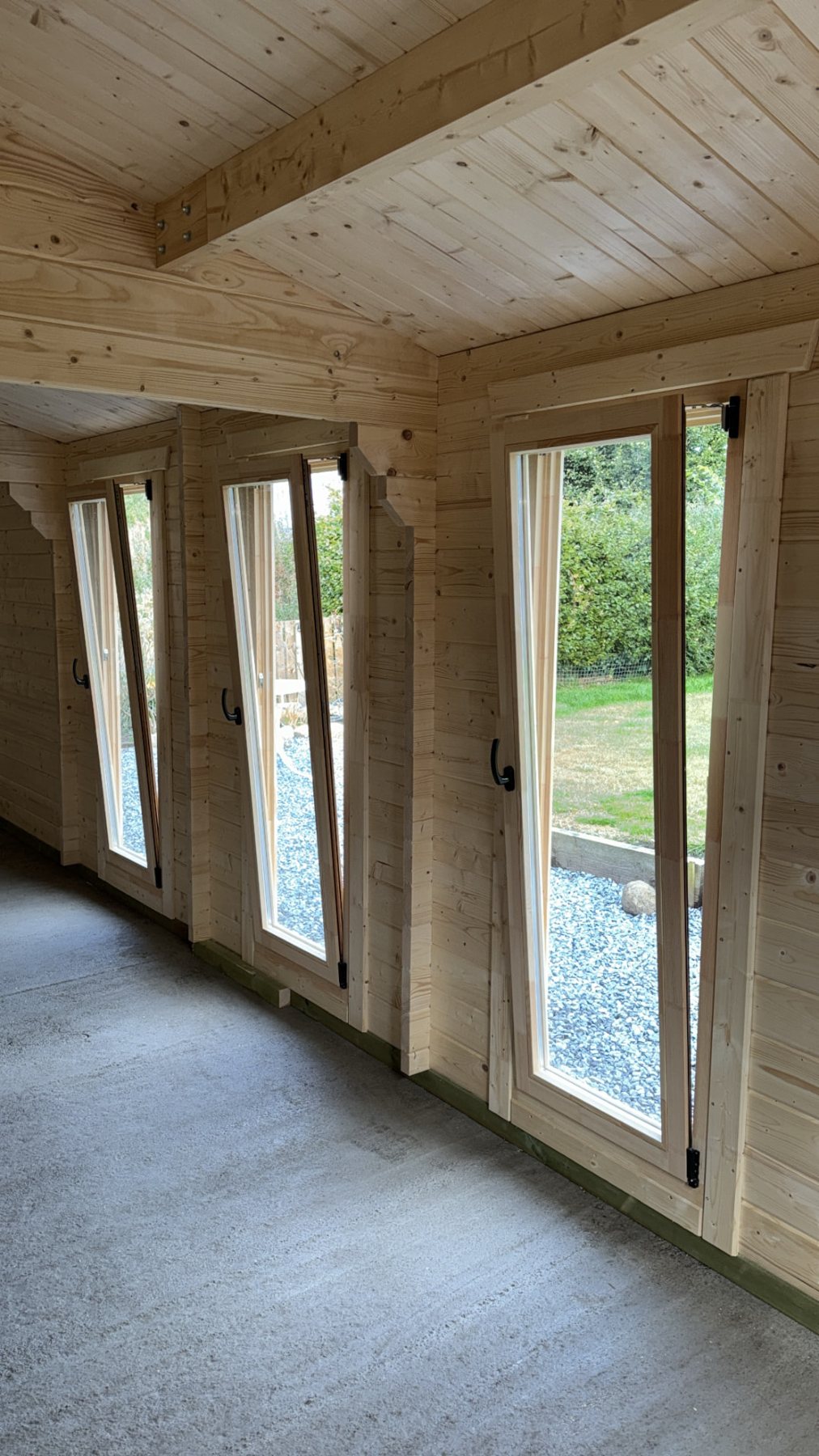 Interior view of an empty log cabin showing exposed timber walls and windows | Signature Garden Rooms, Central Scotland