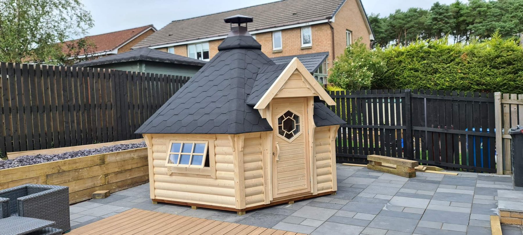 Small wooden BBQ hut with dark shingled roof on a paved garden patio | Signature Garden Rooms, Central Scotland