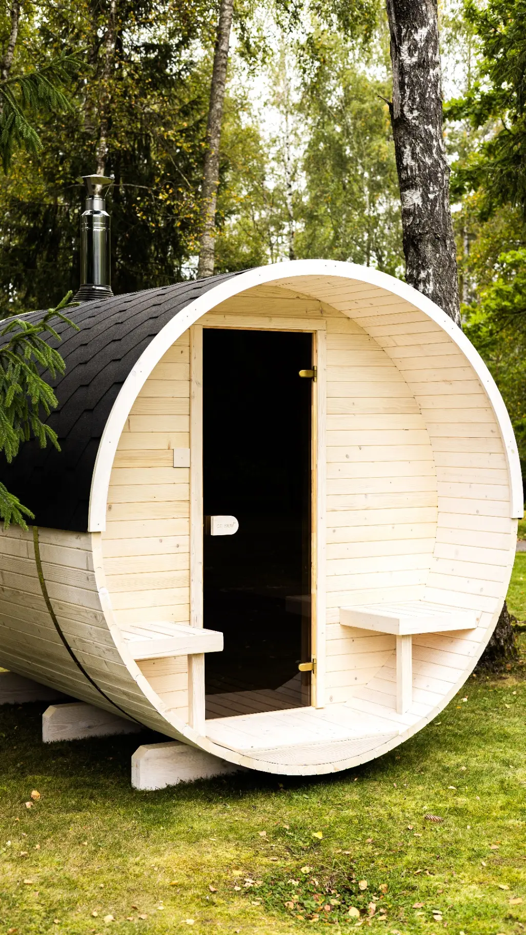 Traditional barrel sauna with black shingle roof and stainless flue