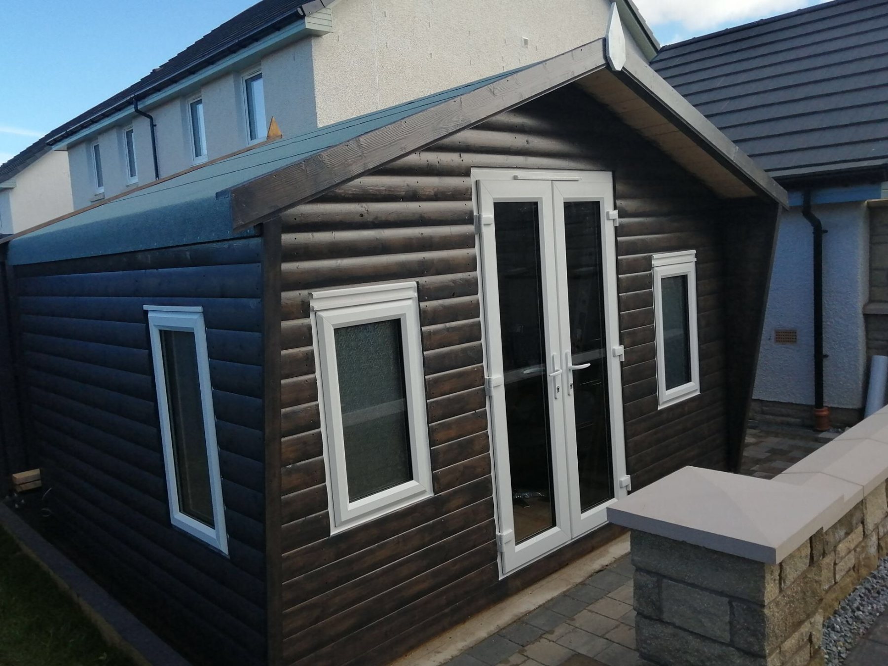 Dark brown timber log cabin with white uPVC double doors and small windows | Signature Garden Rooms, Central Scotland