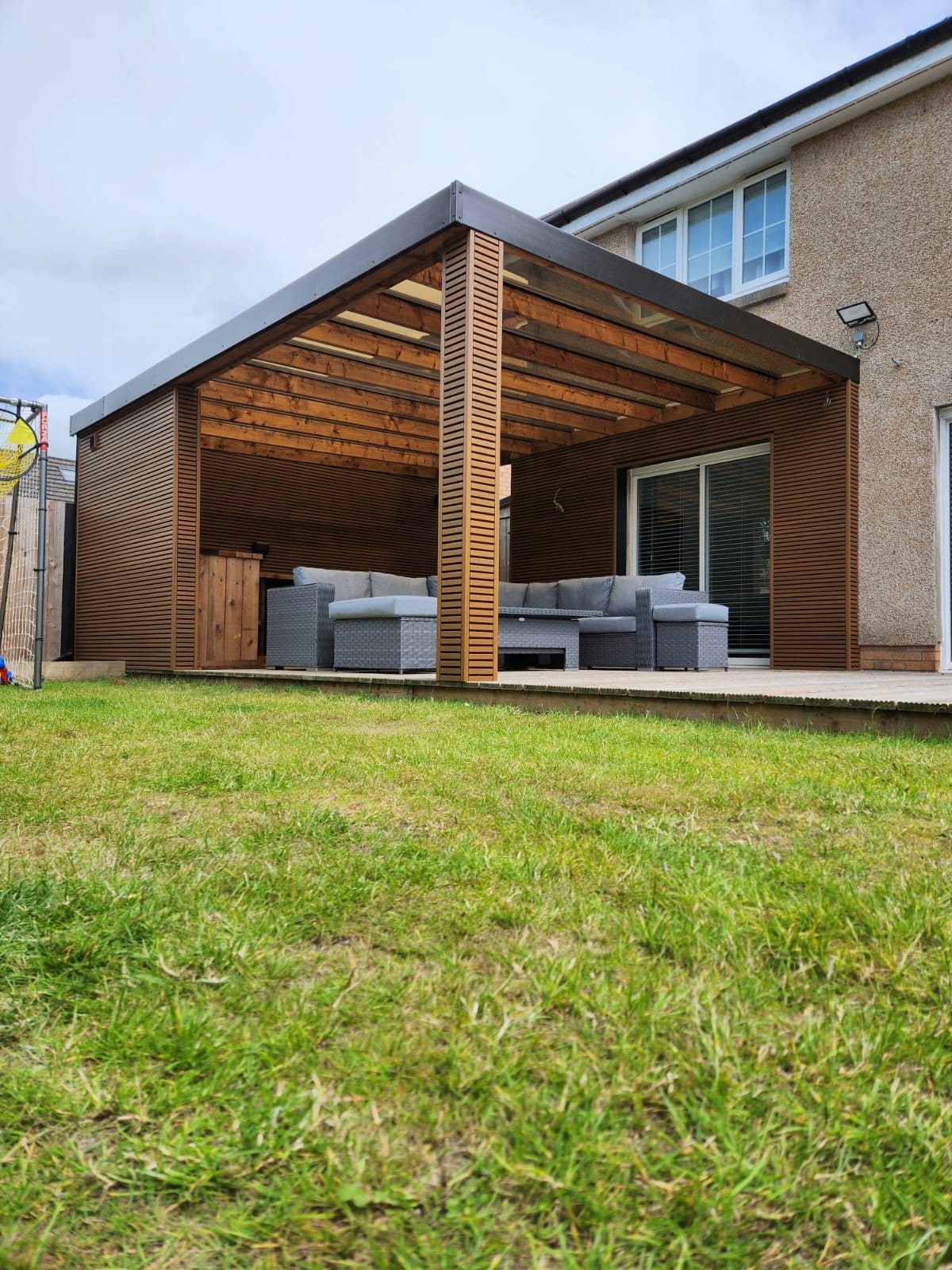 Modern timber garden canopy attached to house with outdoor sofa seating | Signature Garden Rooms, Central Scotland