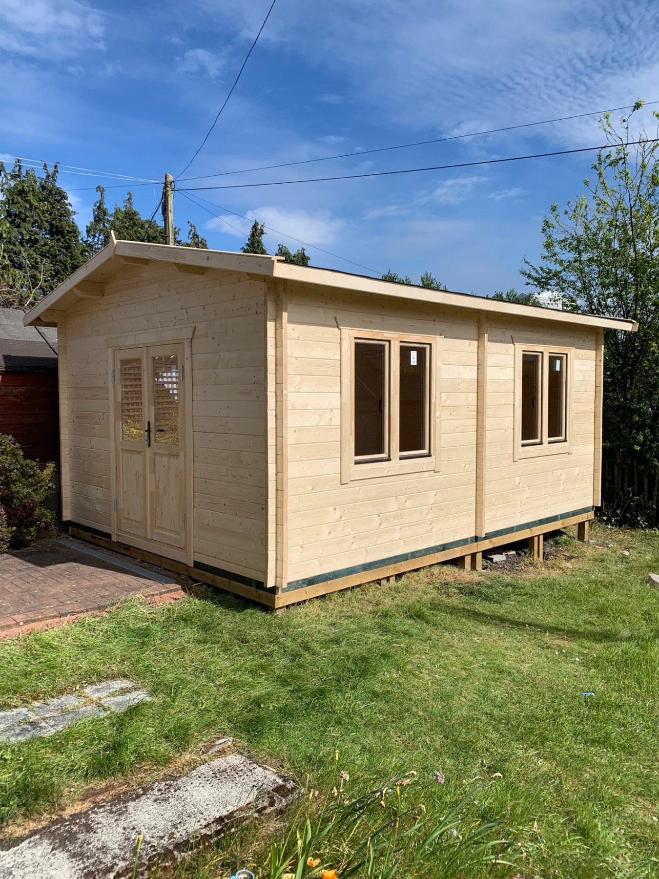 Untreated timber log cabin with double doors and side windows in a garden | Signature Garden Rooms, Central Scotland
