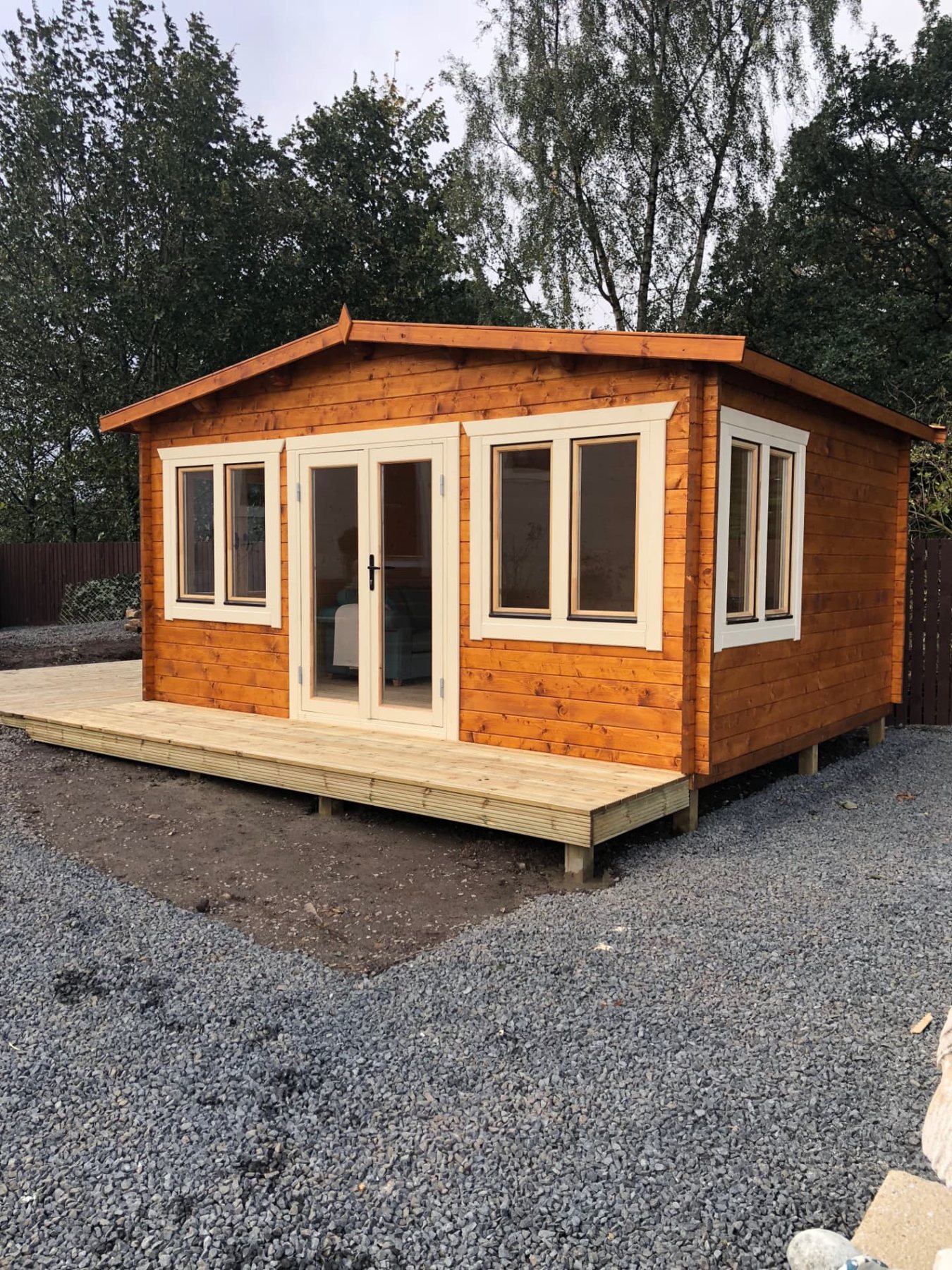 A timber log cabin with double doors, white window frames, and raised decking | Signature Garden Rooms, Central Scotland