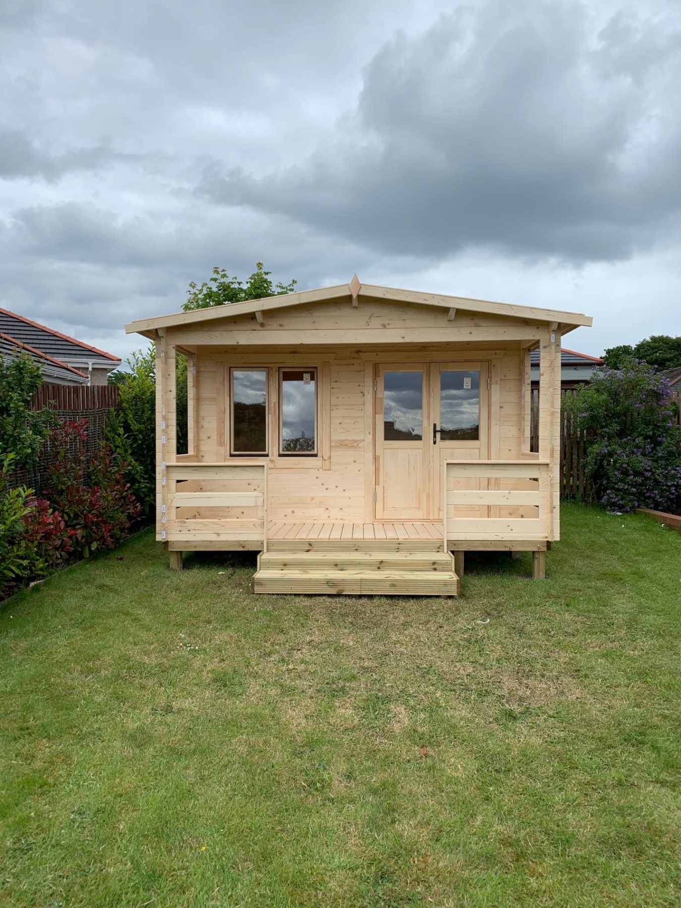 Untreated timber log cabin with covered porch and steps on lawn | Signature Garden Rooms, Central Scotland