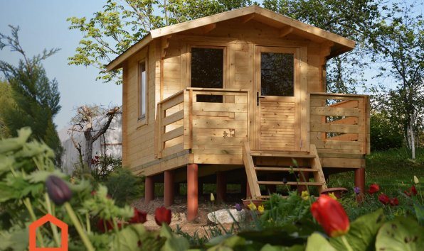 Small elevated wooden log cabin with steps, porch, and surrounding flower garden | Signature Garden Rooms, Central Scotland
