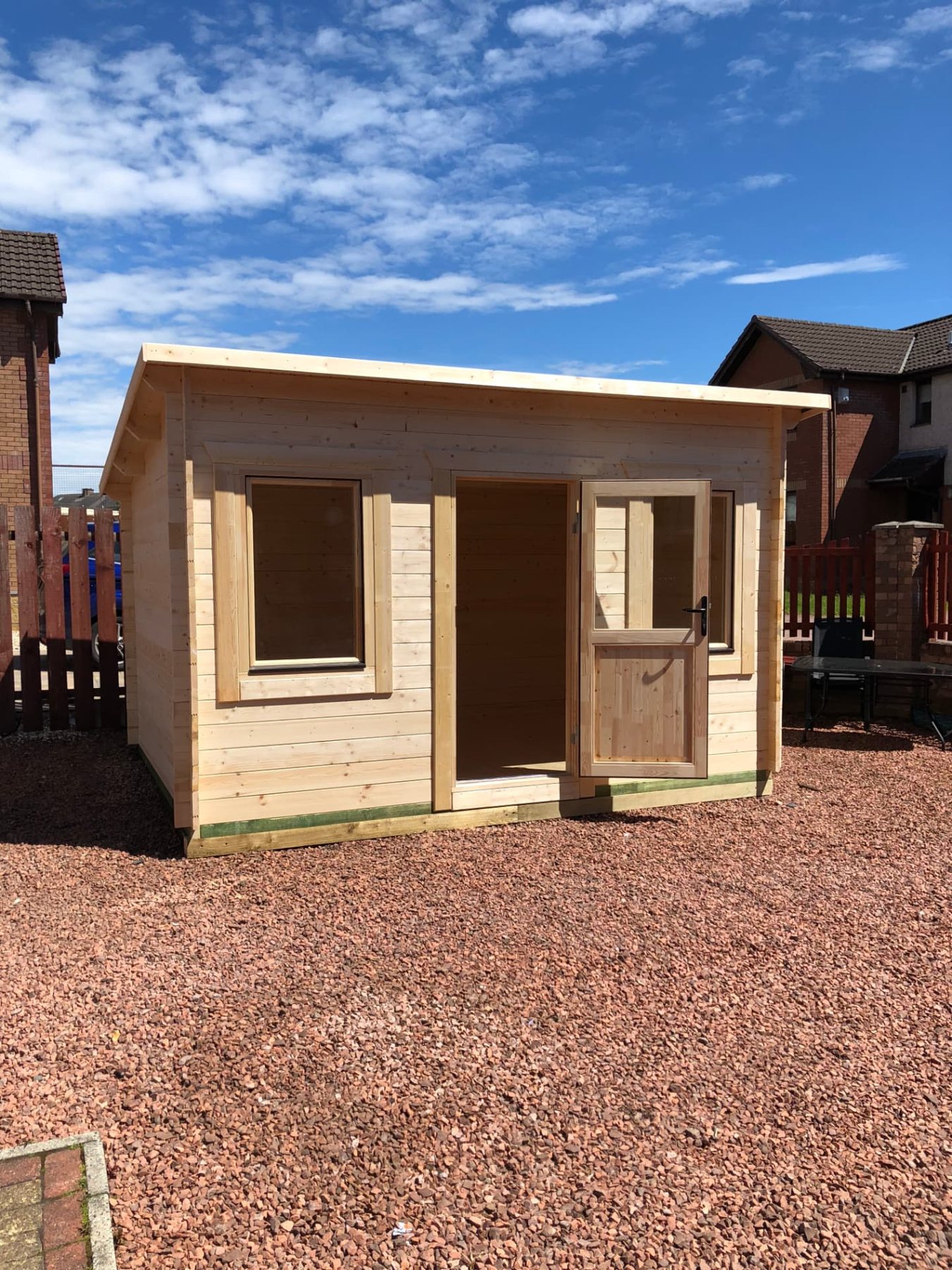 Small untreated timber log cabin with pent roof standing in a gravel garden | Signature Garden Rooms, Central Scotland