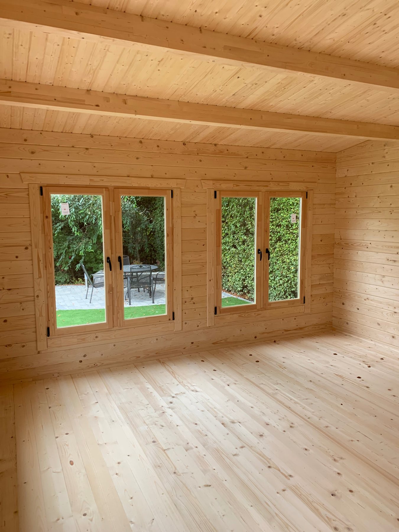 Empty natural timber cabin interior featuring two double windows looking outdoors | Signature Garden Rooms, Central Scotland