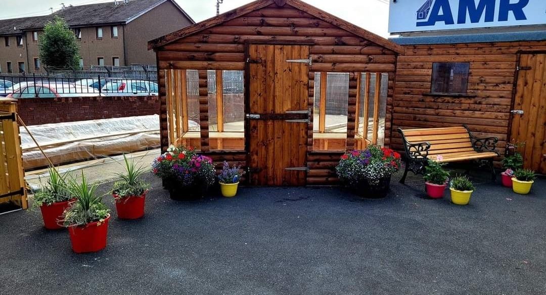 Wooden apex potting shed with glazed windows, central door, and surrounding potted flowers | Signature Garden Rooms, Central Scotland
