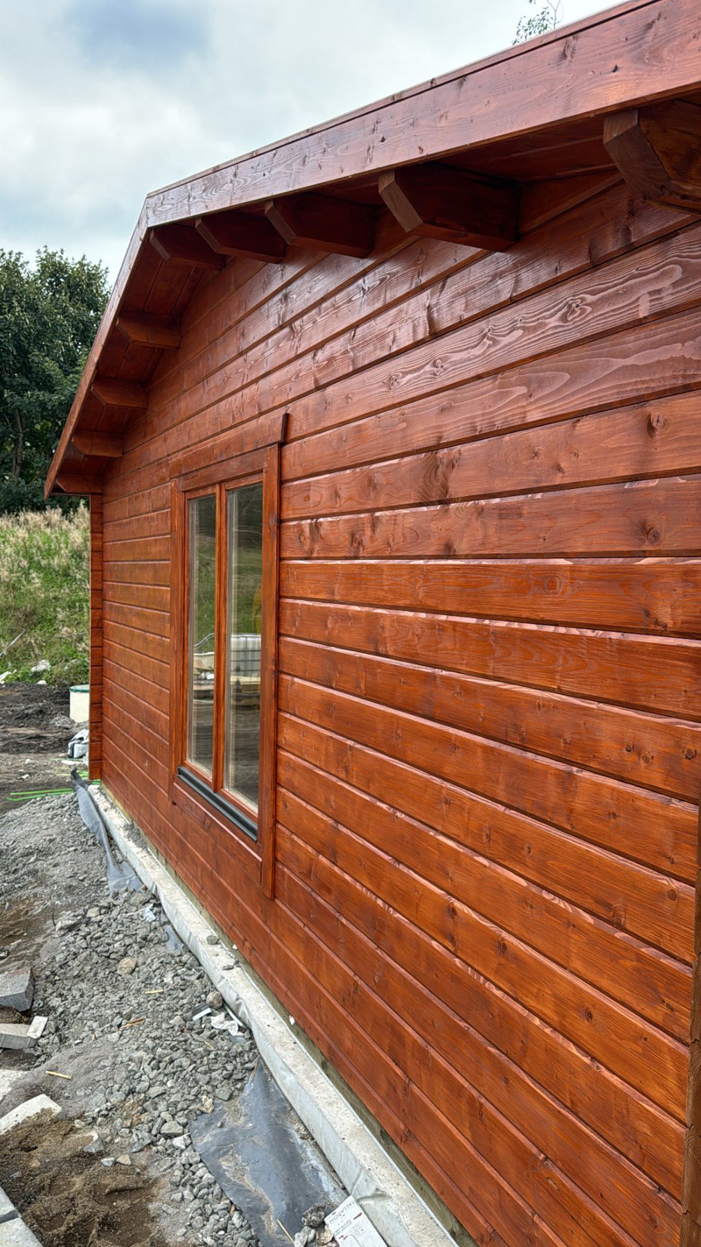 Exterior side elevation of a brown stained timber log cabin under construction | Signature Garden Rooms, Central Scotland