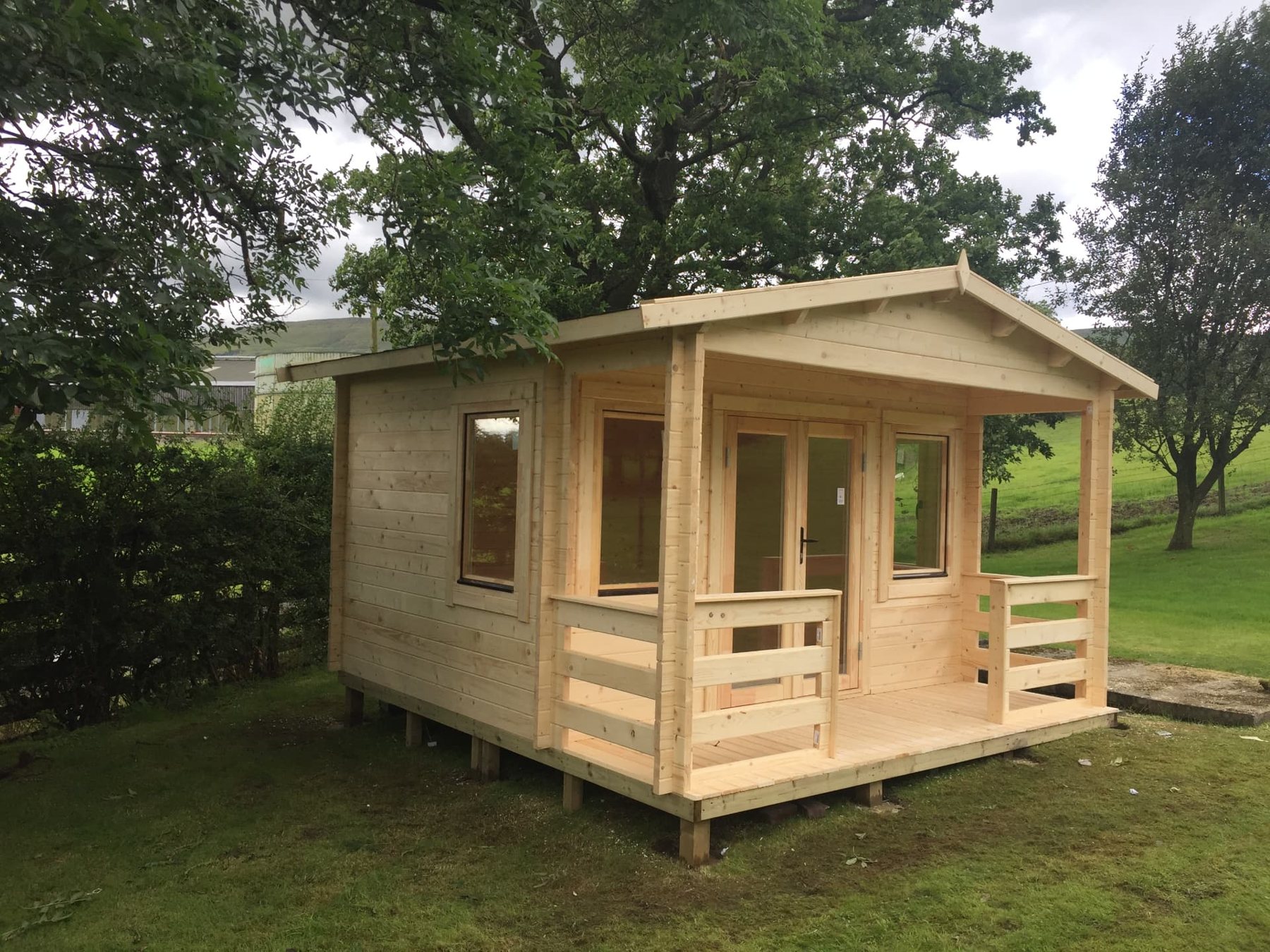 A natural timber log cabin featuring an apex roof and covered veranda | Signature Garden Rooms, Central Scotland