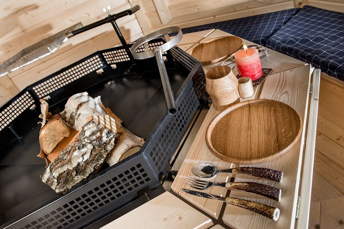 Interior view of a wooden BBQ hut featuring central grill and tableware | Signature Garden Rooms, Central Scotland