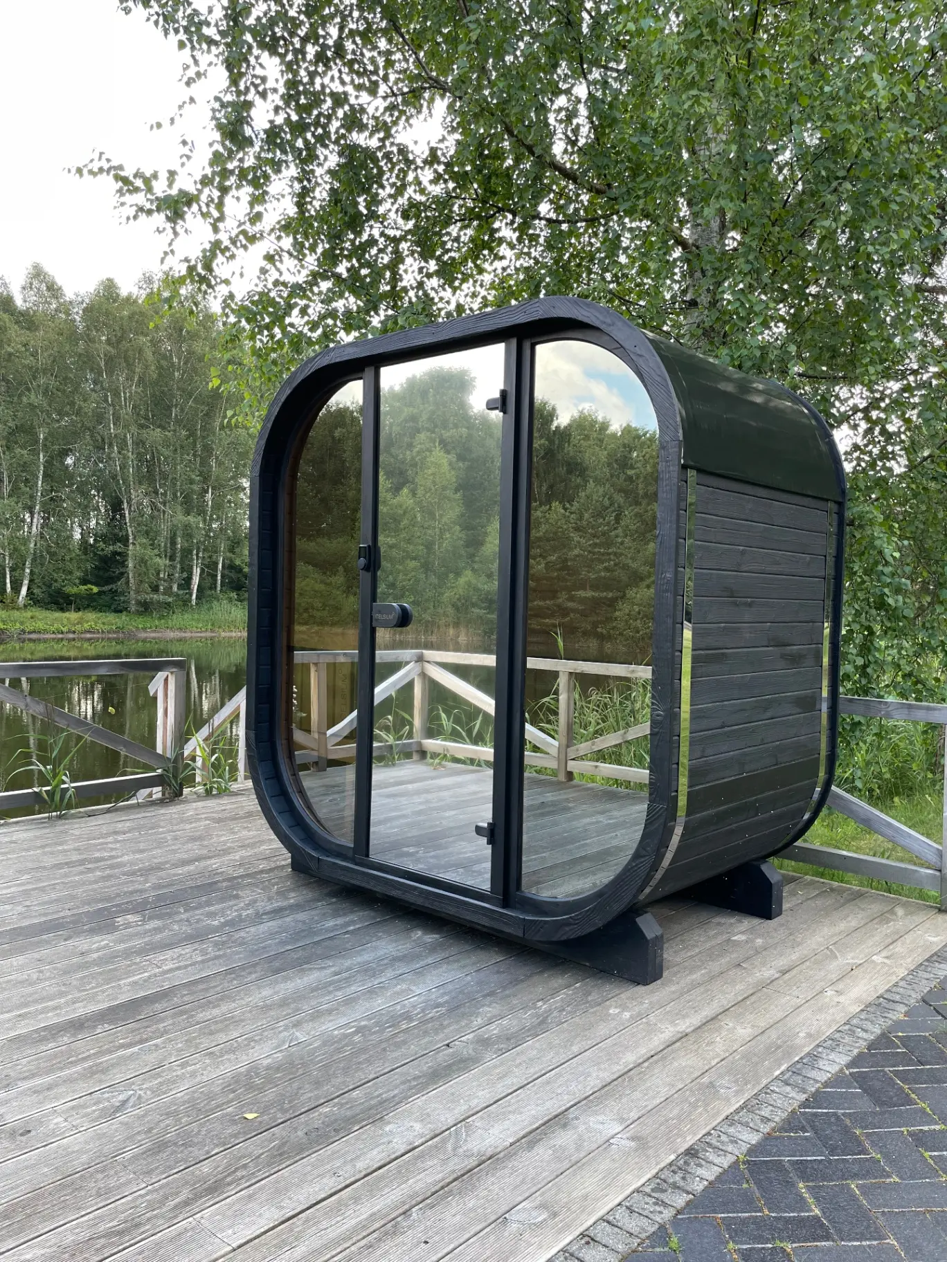 Ebony cube sauna on a lakeside timber deck