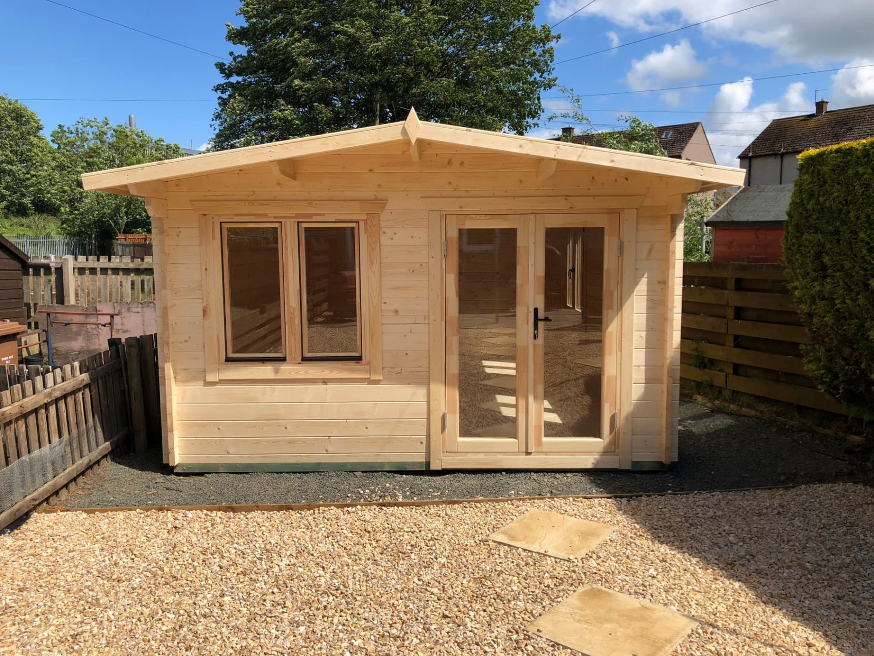 Natural wood interlocking log cabin with double glass doors and windows on gravel | Signature Garden Rooms, Central Scotland