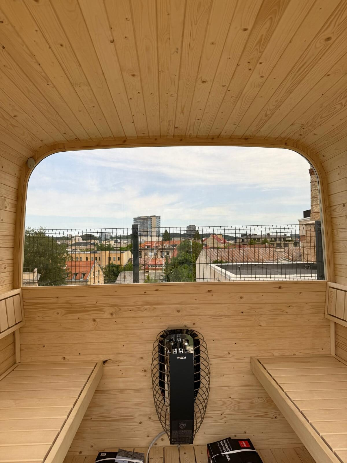 Panoramic rooftop sauna interior with city view and Harvia heater