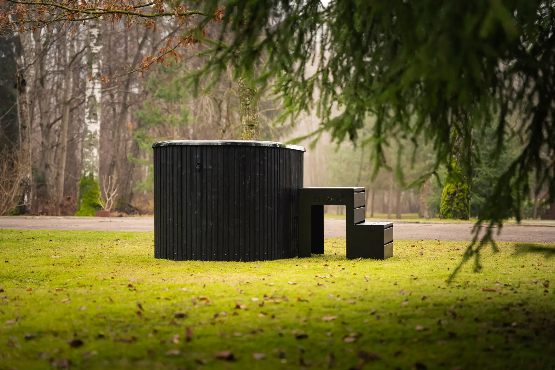 Black wood-panelled round hot tub in a Scottish garden clearing