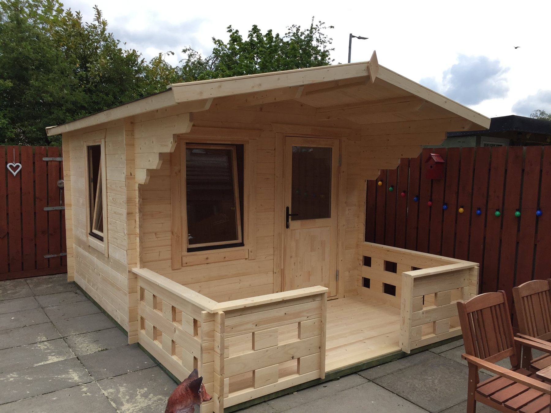 Small light timber log cabin featuring an integrated front veranda on patio | Signature Garden Rooms, Central Scotland
