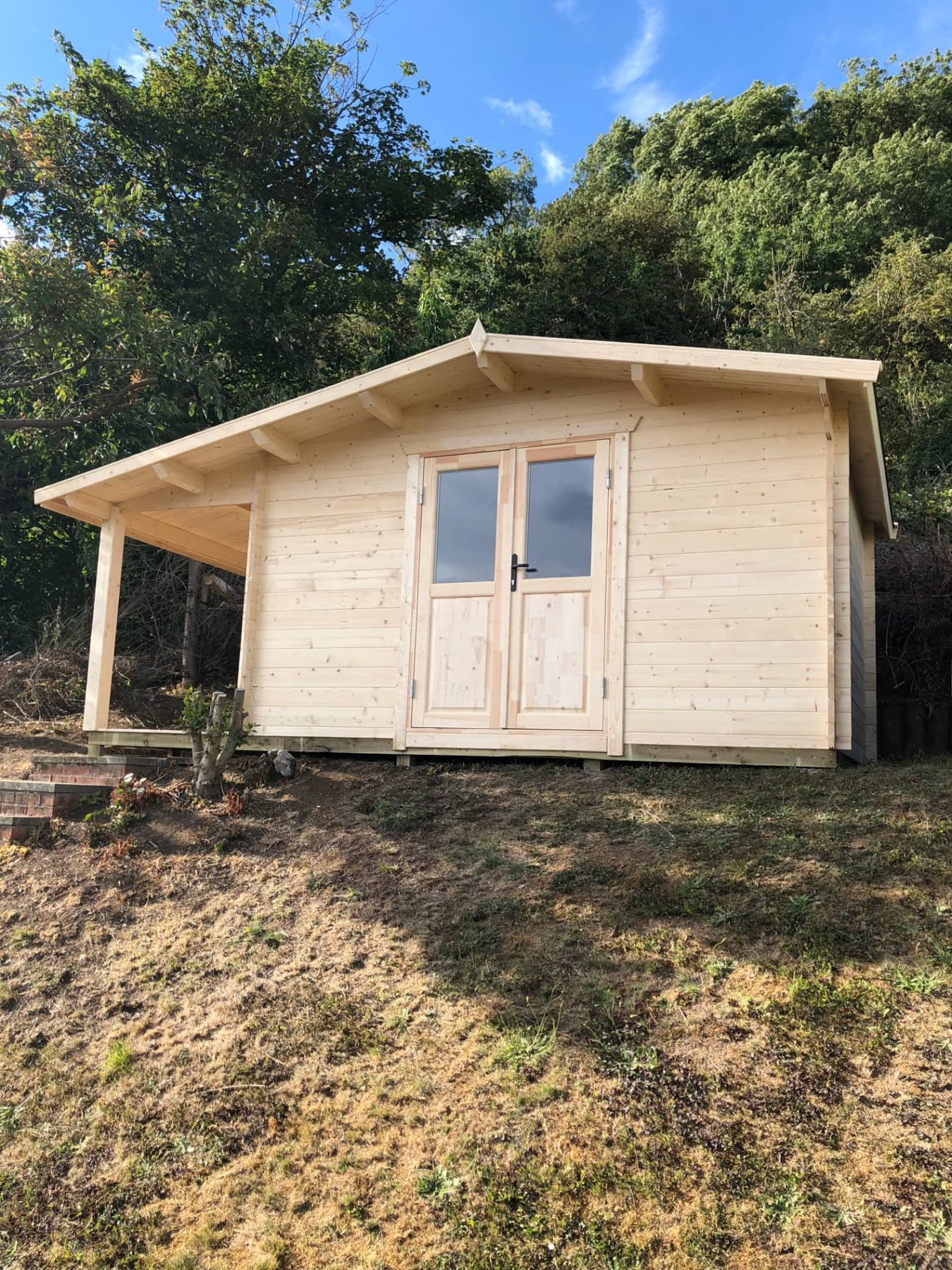 Light timber log cabin with side veranda situated on a grassy slope | Signature Garden Rooms, Central Scotland