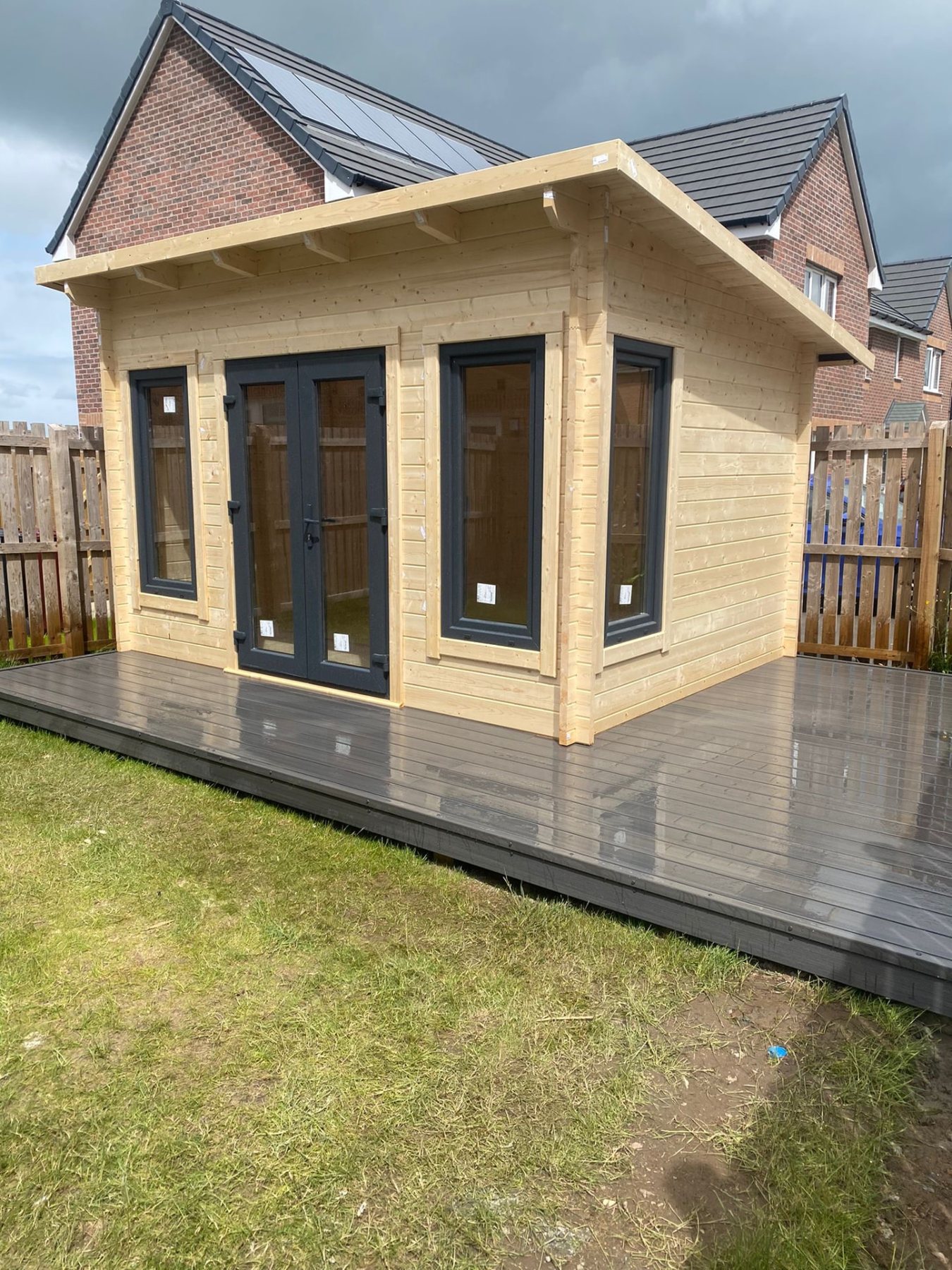 A modern light timber log cabin with dark grey doors on composite decking | Signature Garden Rooms, Central Scotland
