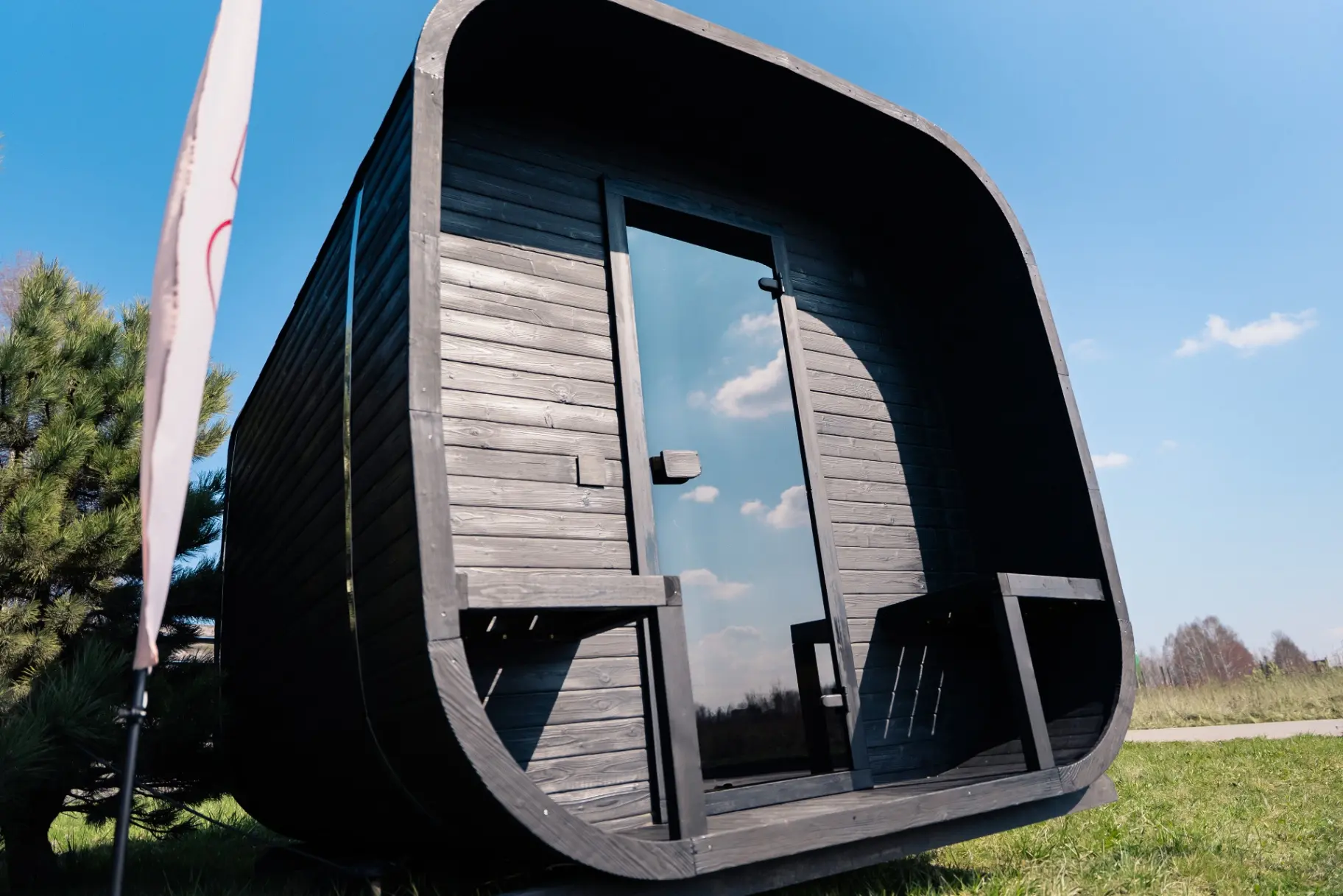 Ebony charred rounded-cube sauna with panoramic glass door