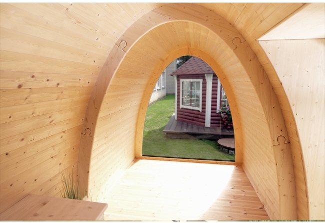 Wooden interior of an arched glamping pod looking out into a garden setting | Signature Garden Rooms, Central Scotland