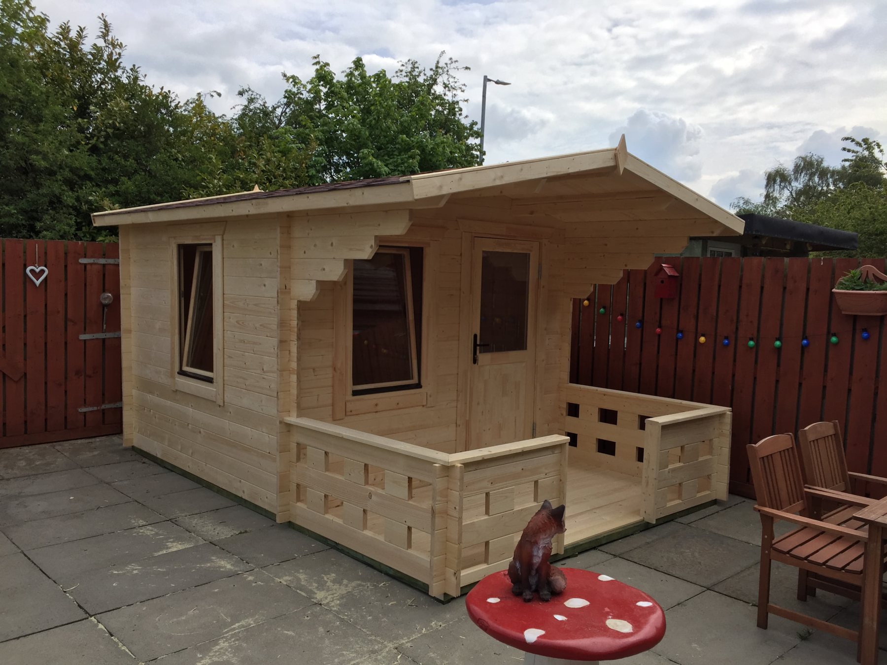 Light-wood log cabin featuring an integrated front porch and open windows in garden | Signature Garden Rooms, Central Scotland