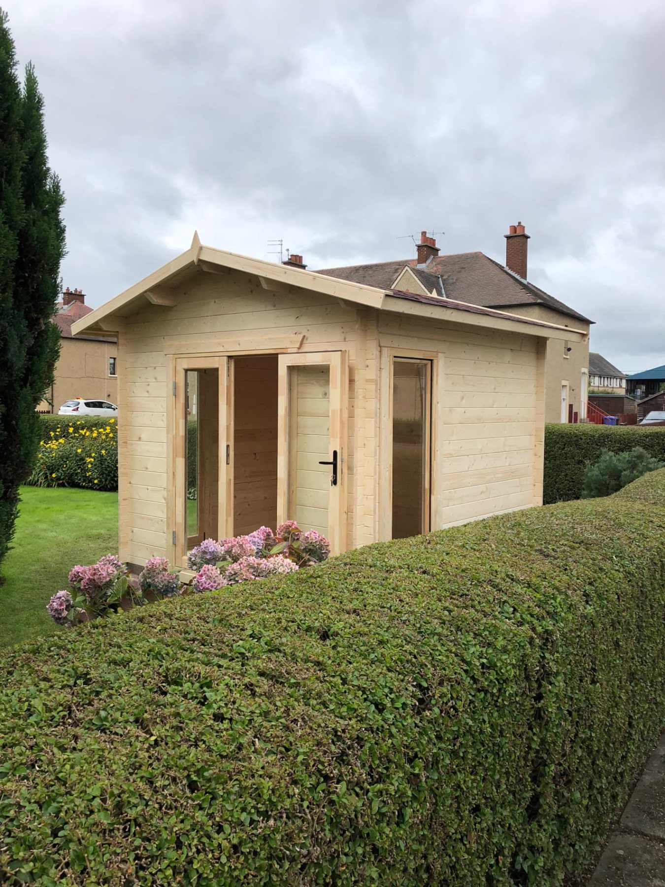 Light timber apex roof log cabin with open glass doors set behind hedge | Signature Garden Rooms, Central Scotland