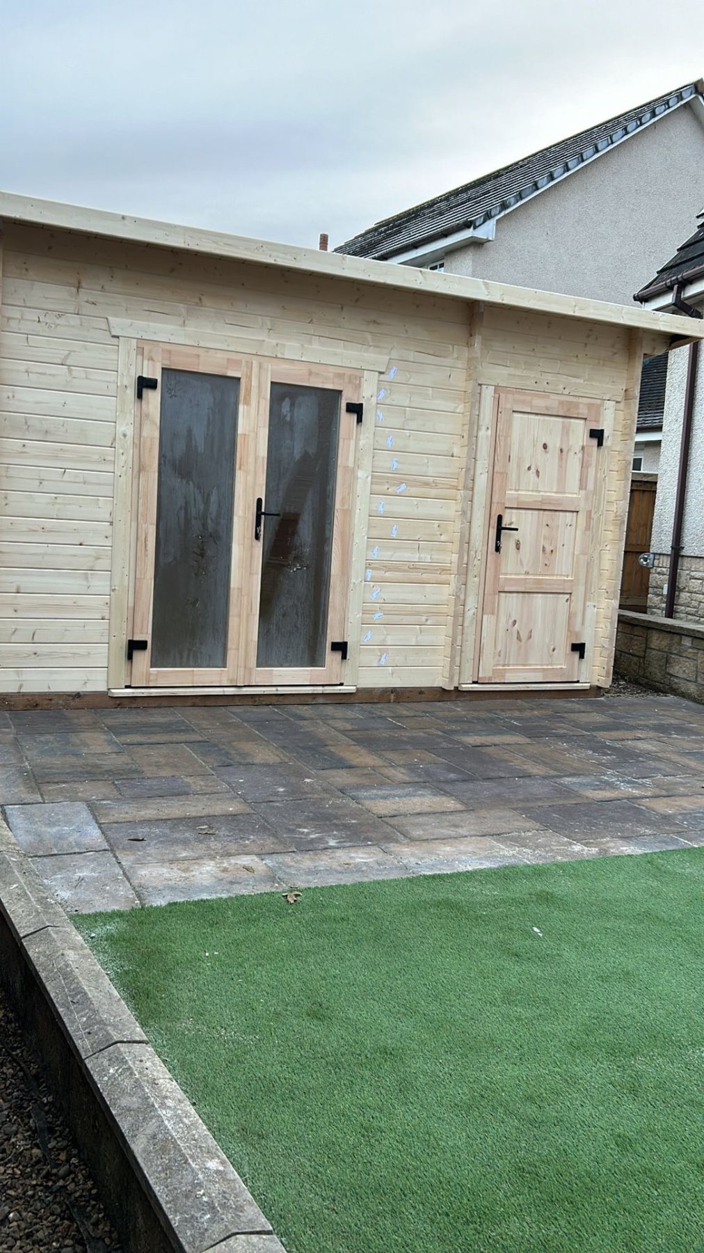 Light timber log cabin featuring glazed double doors and an adjacent side storage door | Signature Garden Rooms, Central Scotland
