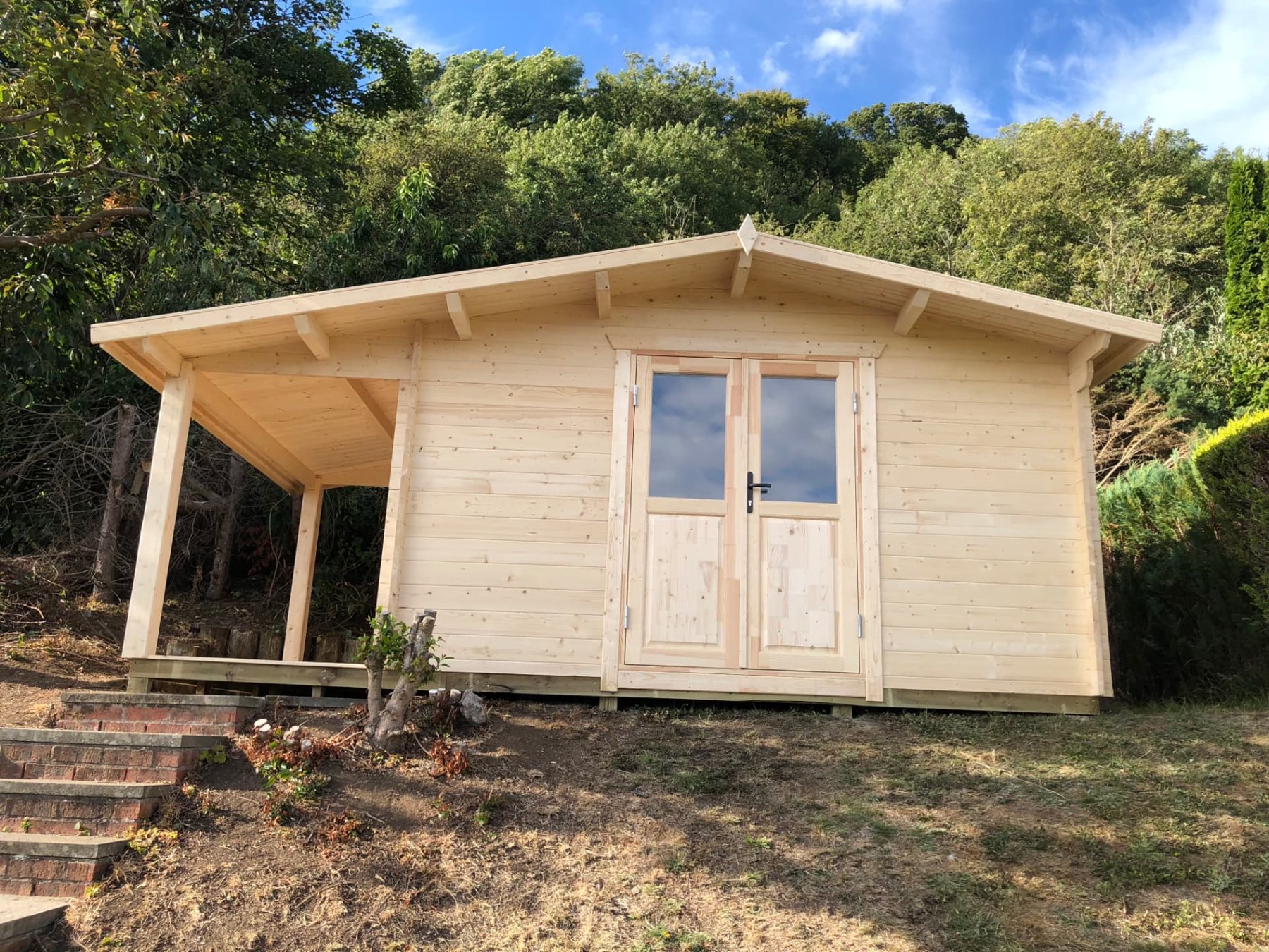 A light timber log cabin with double doors and an attached side canopy | Signature Garden Rooms, Central Scotland