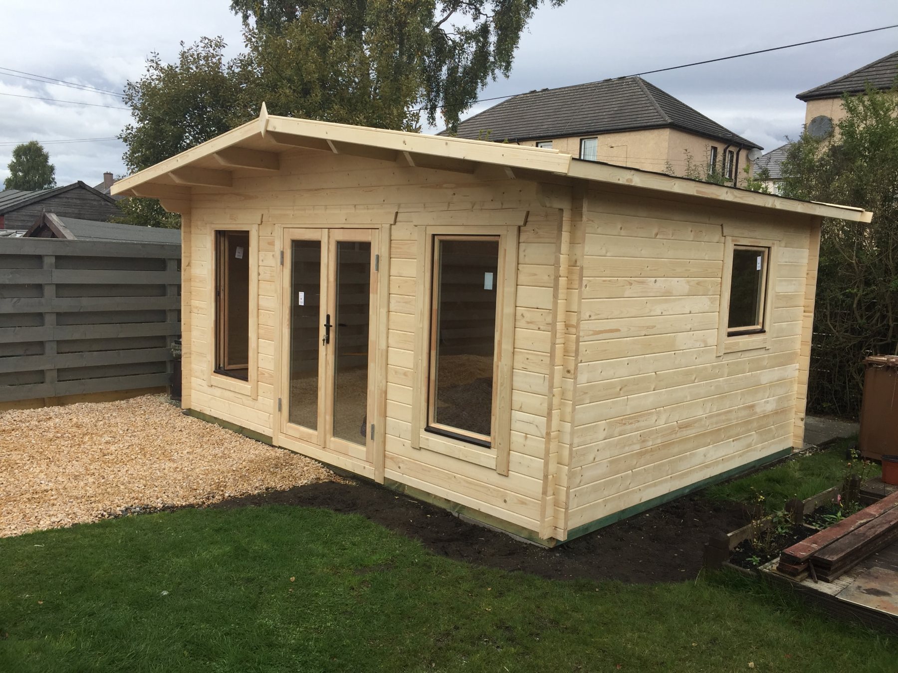 Natural timber log cabin with double doors installed in a gravelled residential garden | Signature Garden Rooms, Central Scotland