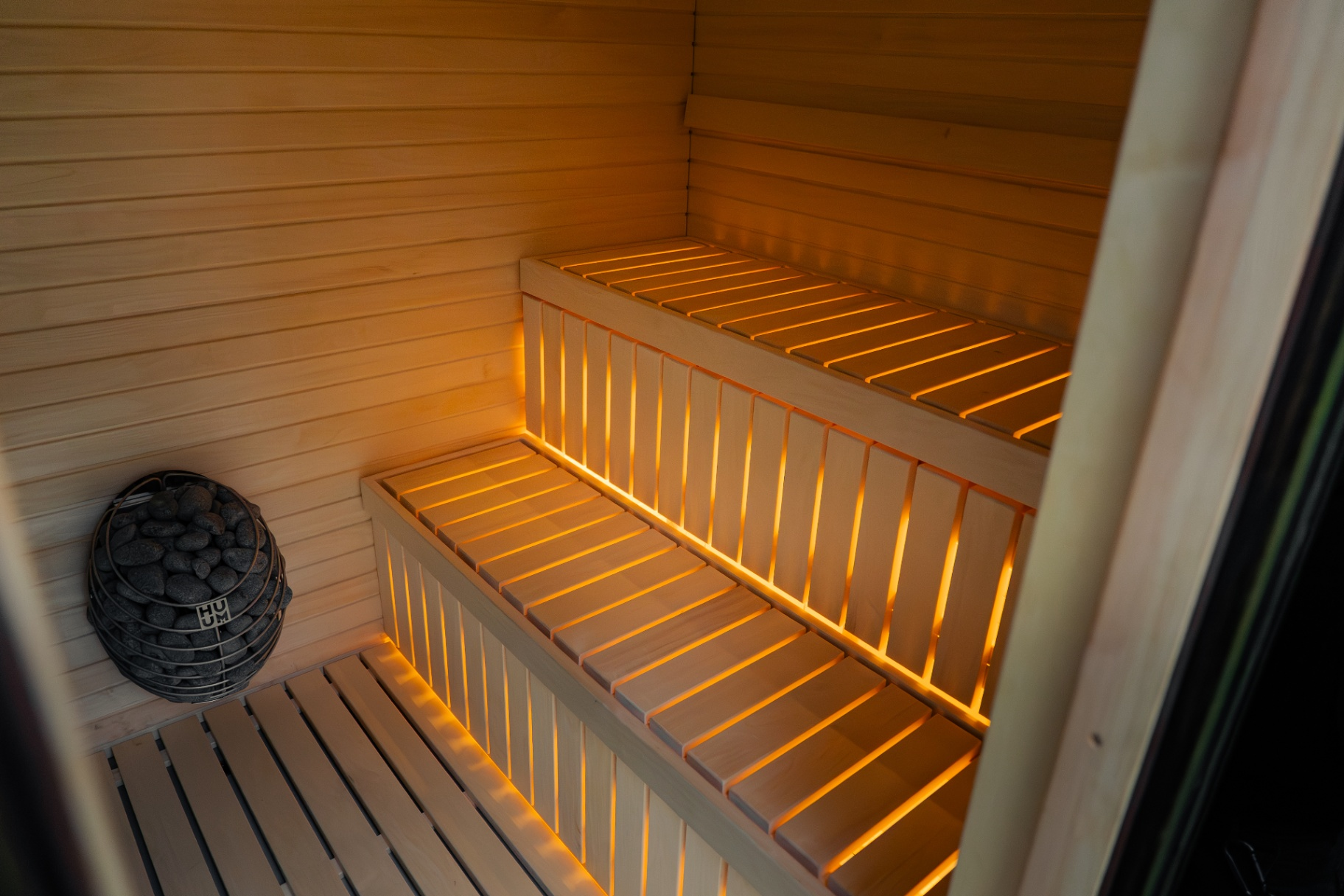 Interior of a modular sauna with HUUM heater and warm LED bench lighting