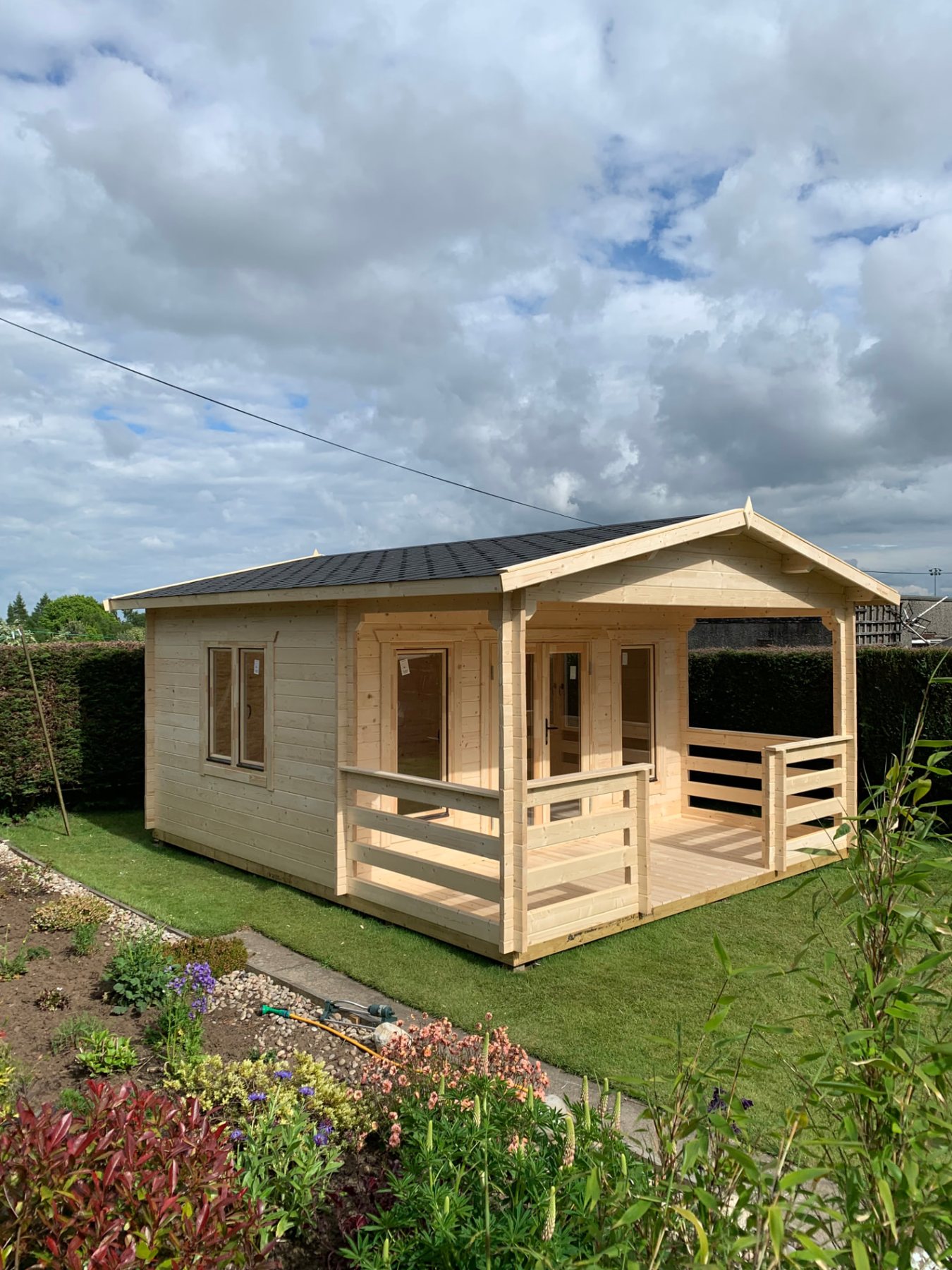 Light wood log cabin with a covered veranda standing on a grassy lawn | Signature Garden Rooms, Central Scotland
