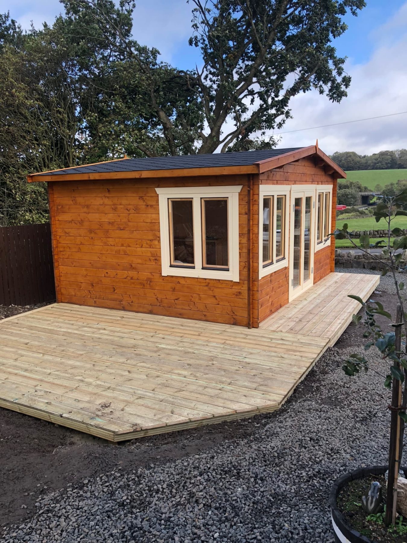 A wooden log cabin with cream windows and doors on timber decking | Signature Garden Rooms, Central Scotland
