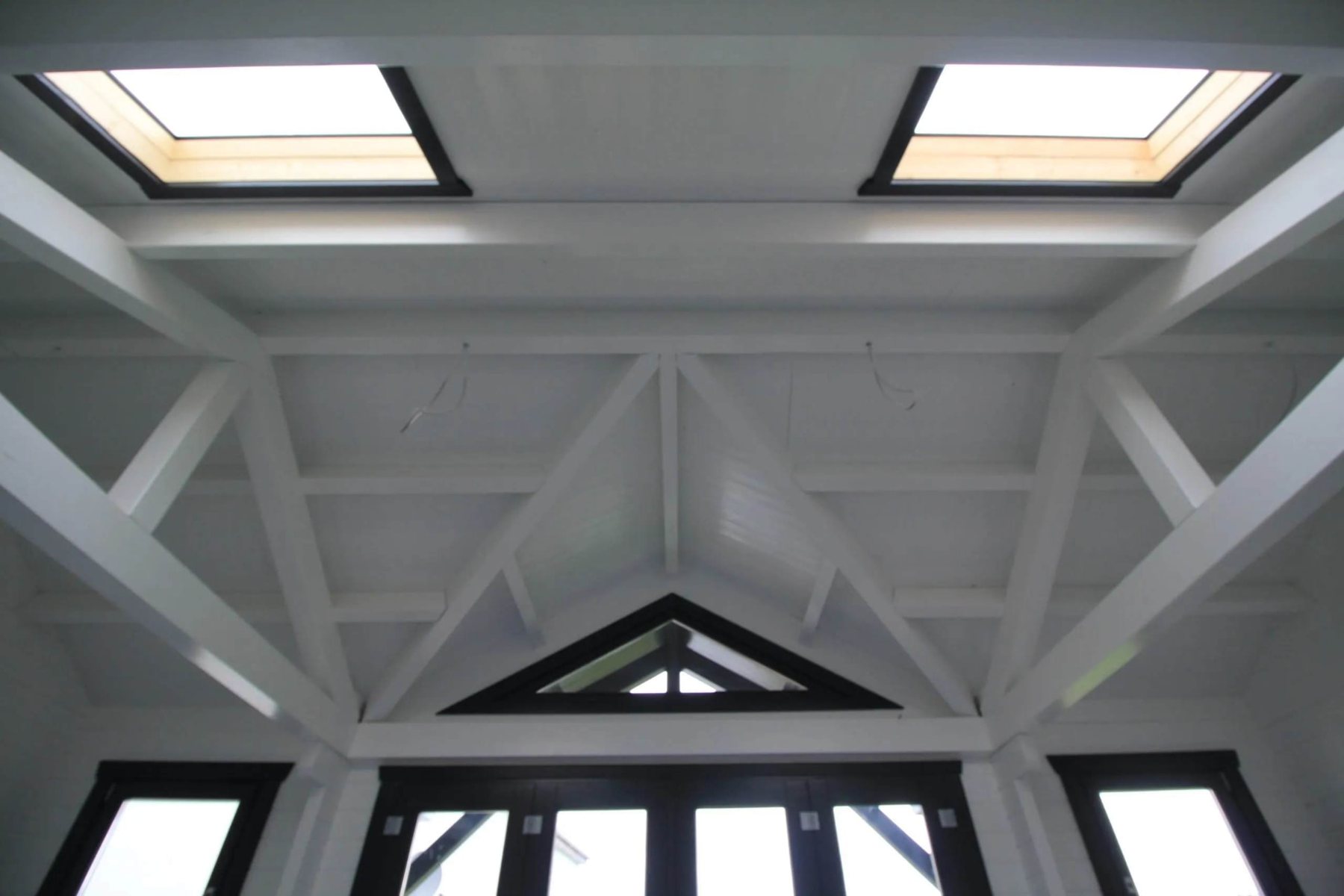 Interior view showing white painted roof trusses with skylights and dark frames | Signature Garden Rooms, Central Scotland