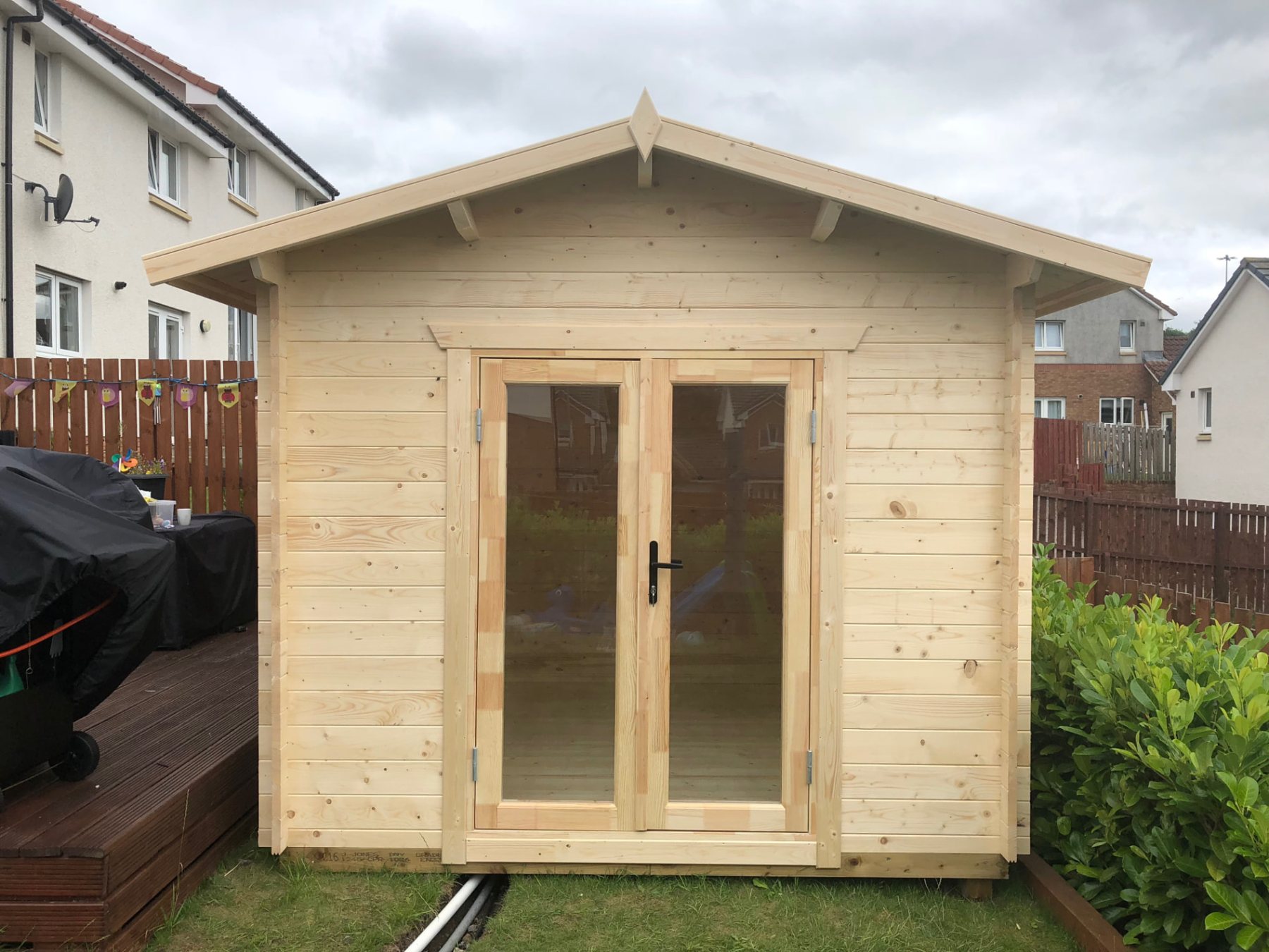 Front view of a small untreated timber log cabin with double glass doors | Signature Garden Rooms, Central Scotland