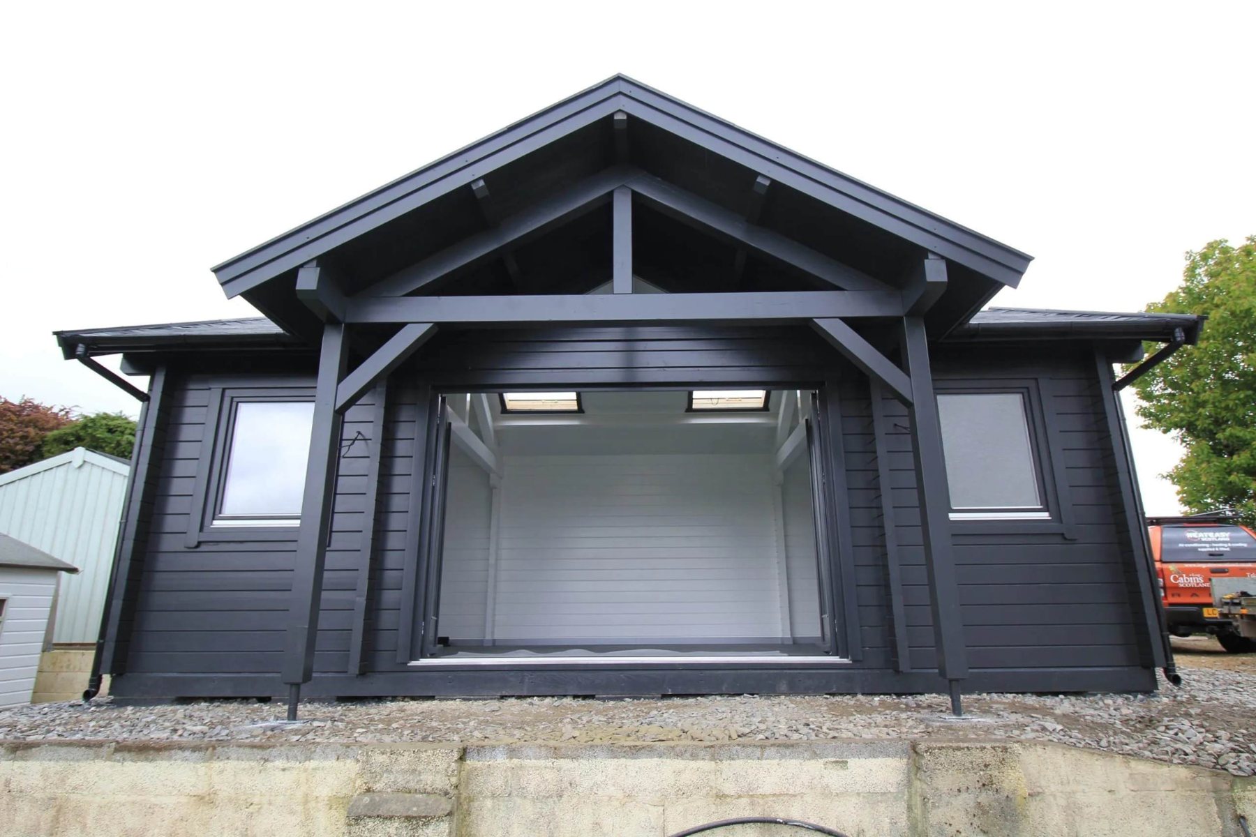 Dark painted timber log cabin featuring an apex roof overhang and large opening | Signature Garden Rooms, Central Scotland