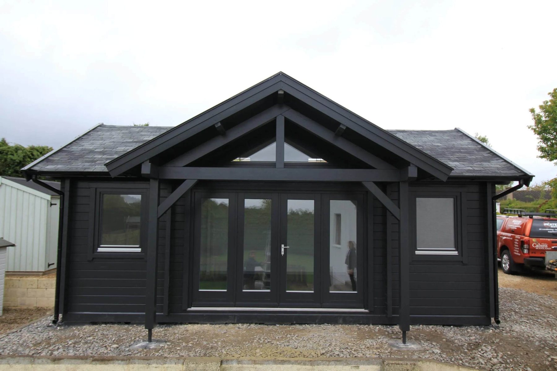 Large black painted log cabin with apex roof and central glass bi-fold doors | Signature Garden Rooms, Central Scotland